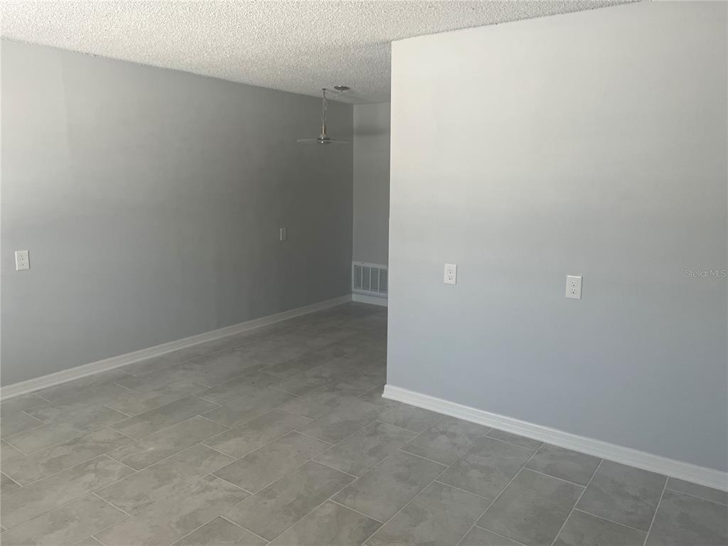 A room with gray walls, light-colored tile flooring, and a textured white ceiling — 4945 ELKNER STREET, NEW PORT RICHEY, FL