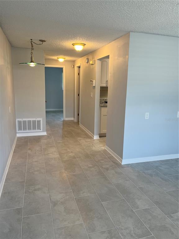 A hallway with gray tile flooring leads to a kitchen and other rooms — 4945 ELKNER STREET, NEW PORT RICHEY, FL