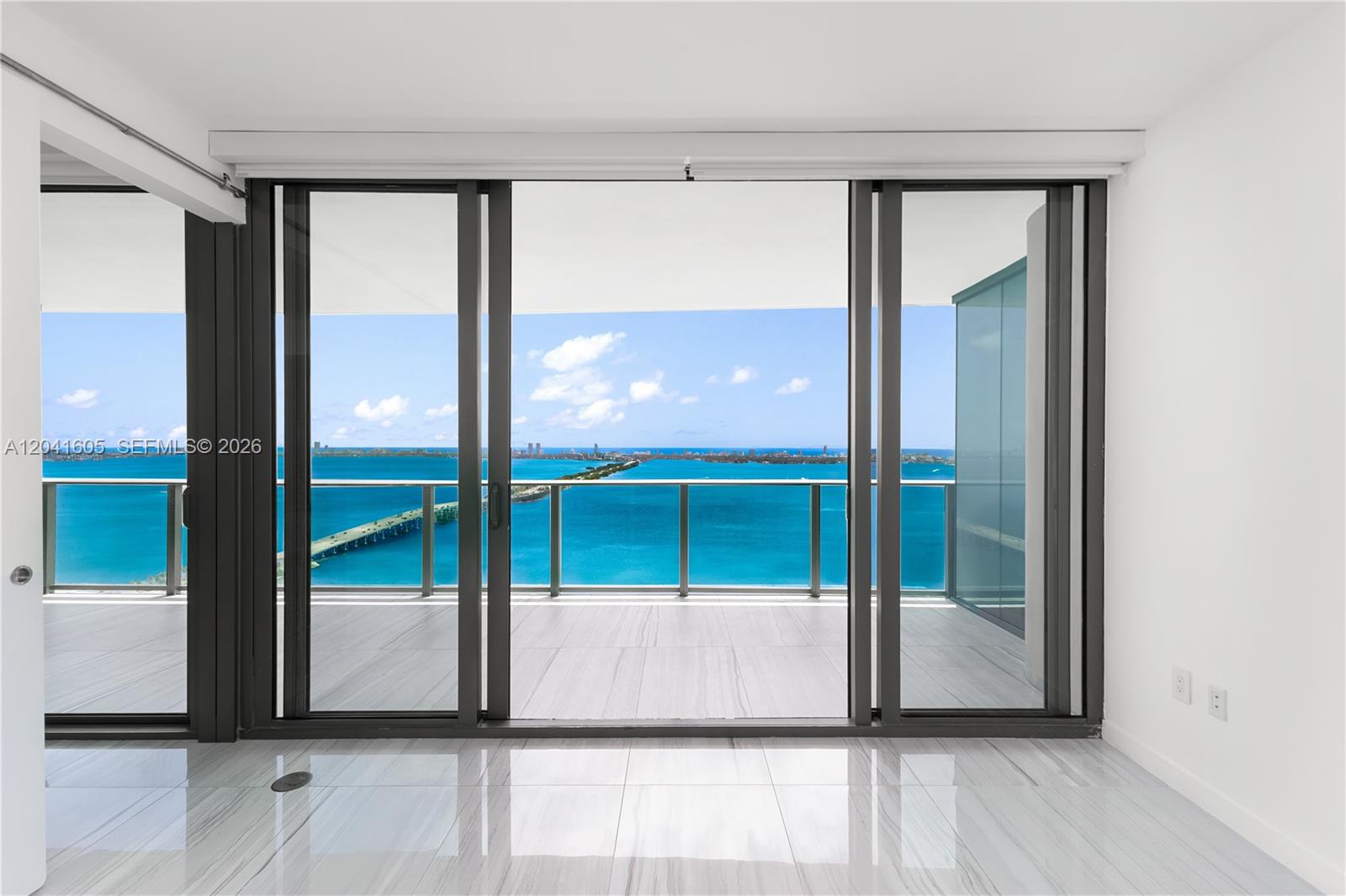 An interior room with white tile floors features large sliding glass doors opening to a balcony — 3131 NE 7th Ave # 4102, Miami FL 33137, MIAMI, FL