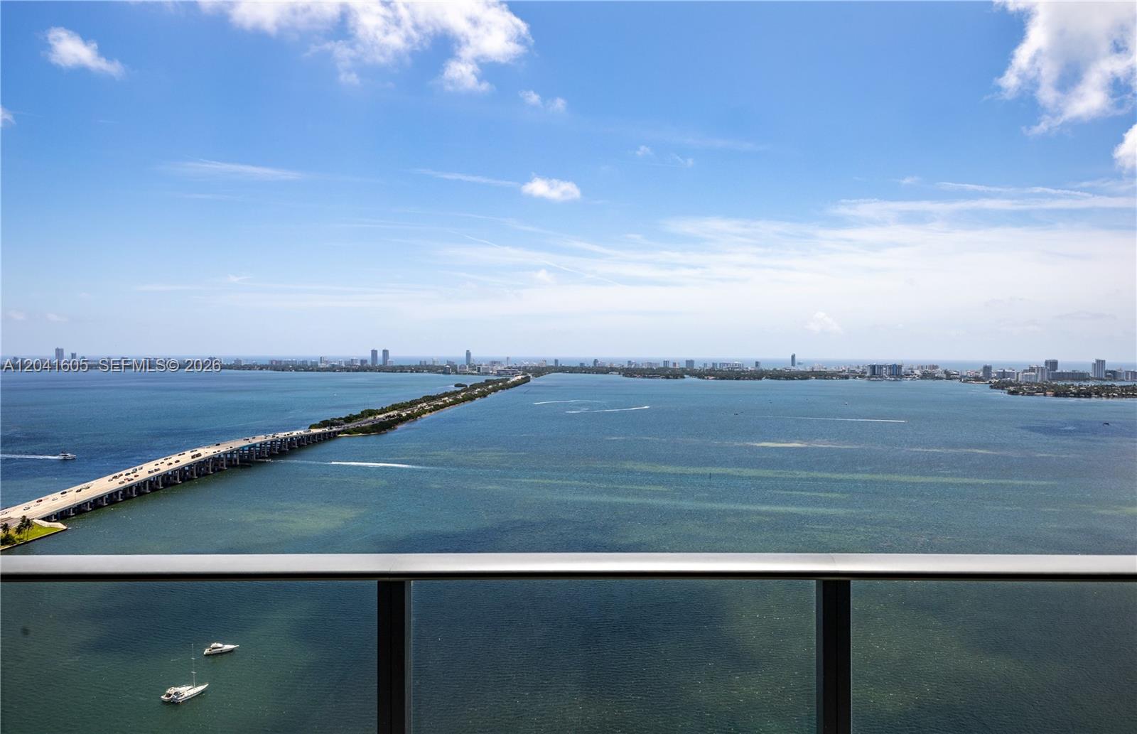 A high-angle view from a balcony overlooks a long bridge spanning a large bay — 3131 NE 7th Ave # 4102, Miami FL 33137, MIAMI, FL