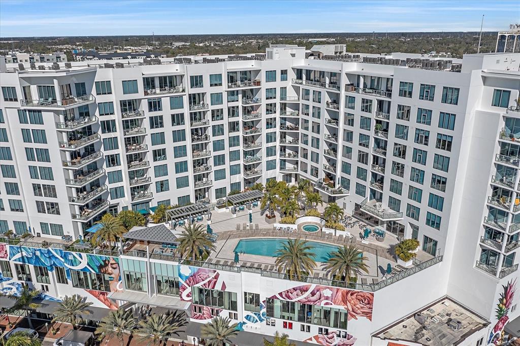 An aerial view of a multi-story apartment building featuring a central pool deck and murals — 111 S PINEAPPLE AVENUE UNIT 601, SARASOTA, FL