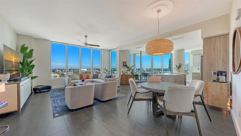 A modern open-concept living and dining area features floor-to-ceiling windows and tile flooring — 111 S PINEAPPLE AVENUE UNIT 601, SARASOTA, FL