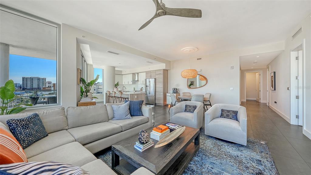 A modern open-concept living room features a grey sectional, two armchairs, and a kitchen area — 111 S PINEAPPLE AVENUE UNIT 601, SARASOTA, FL