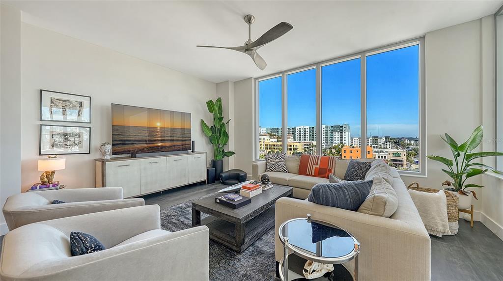 A modern living room features a large sectional sofa, two armchairs, and floor-to-ceiling windows — 111 S PINEAPPLE AVENUE UNIT 601, SARASOTA, FL