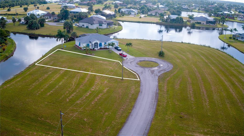 An aerial view shows a vacant residential lot outlined in white next to a house — 24070 CHERRYSTONE LANE, PUNTA GORDA, FL