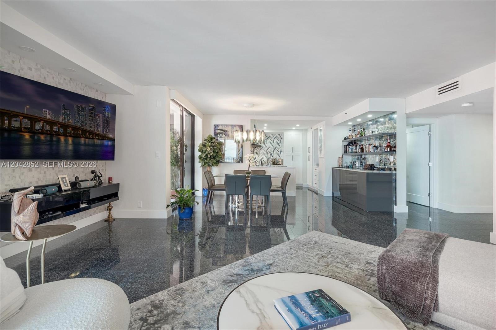 A modern living and dining area features dark polished stone floors and a built-in bar — 1581 Brickell Ave # 1805, Miami FL 33129, MIAMI, FL