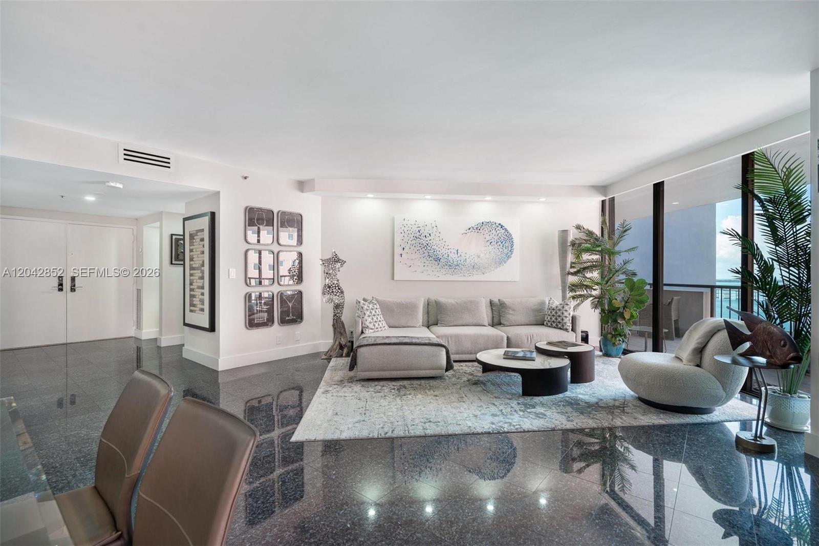 A modern living room features dark polished floors, a grey sectional sofa, and floor-to-ceiling windows — 1581 Brickell Ave # 1805, Miami FL 33129, MIAMI, FL