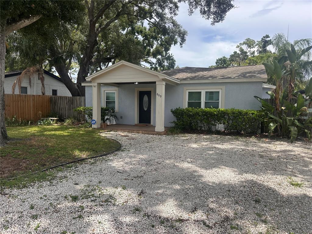 A light blue single-story house features a covered front porch and a gravel driveway — 809 W HIAWATHA STREET, TAMPA, FL
