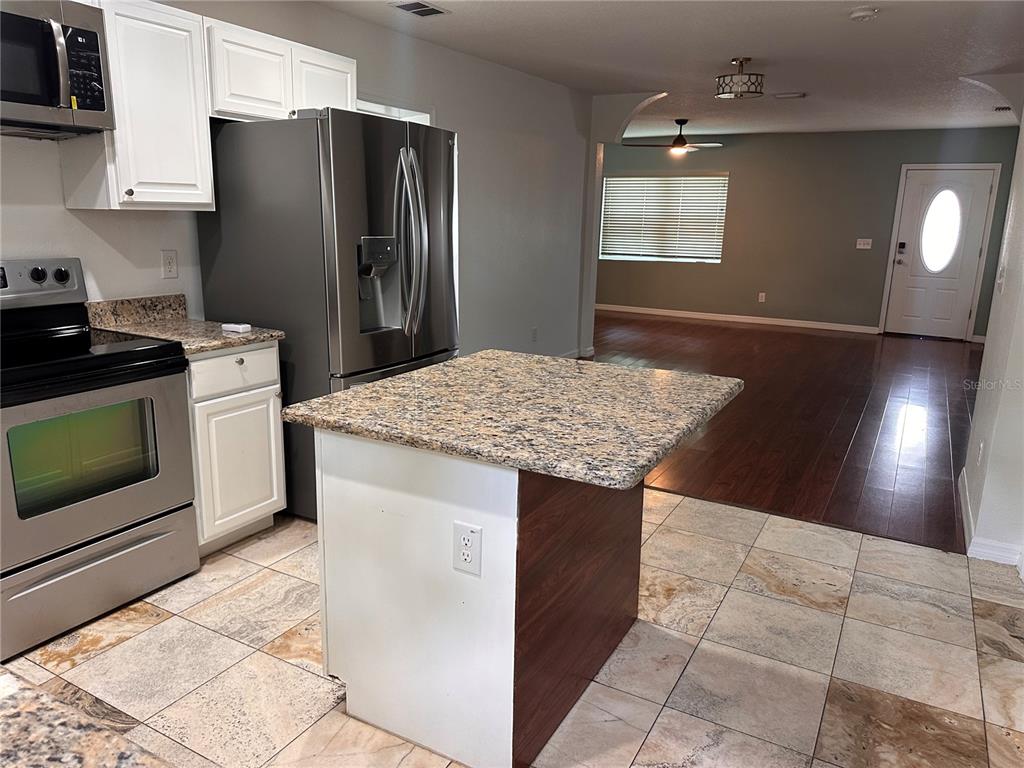 A kitchen with white cabinets, stainless steel appliances, and a granite-topped island — 809 W HIAWATHA STREET, TAMPA, FL