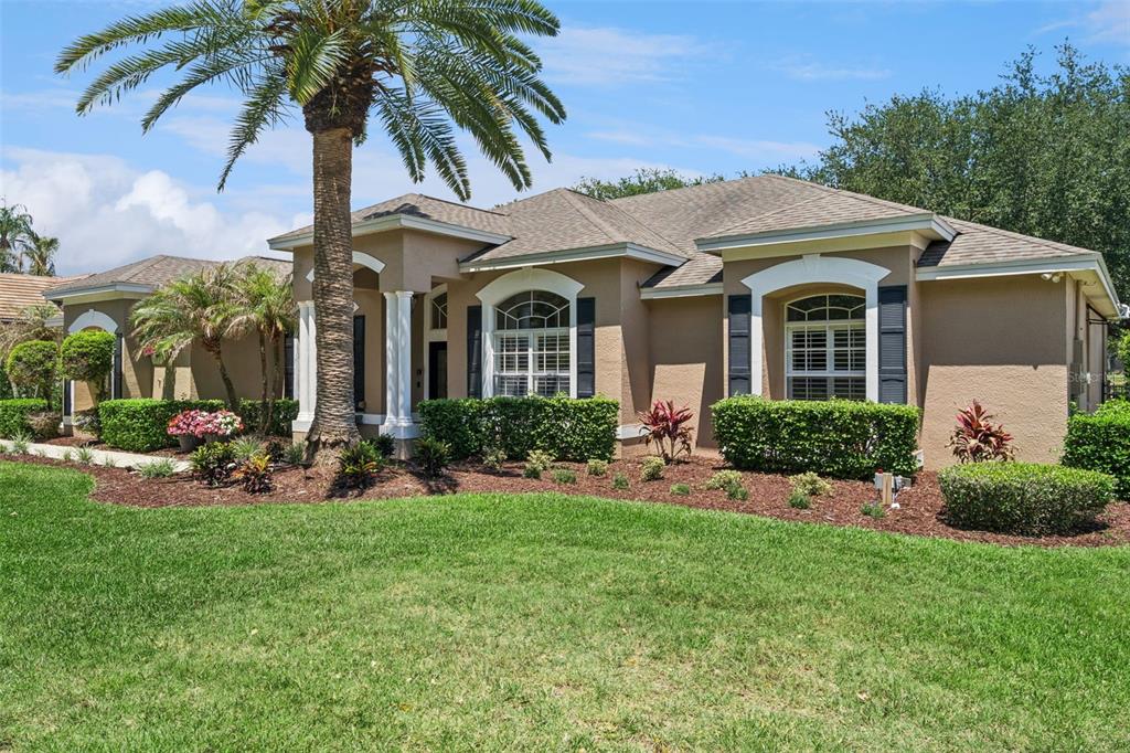 A tan single-story house with a palm tree, manicured hedges, and a concrete driveway — 2230 RIDGEWIND WAY, WINDERMERE, FL