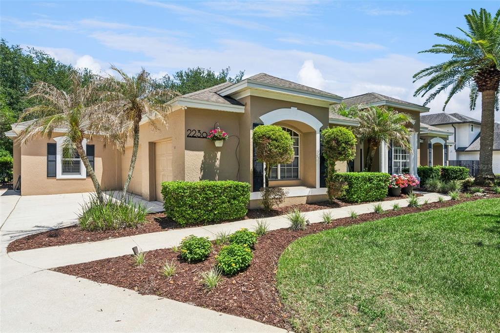 A single-story tan house with a palm tree, arched windows, and manicured landscaping — 2230 RIDGEWIND WAY, WINDERMERE, FL