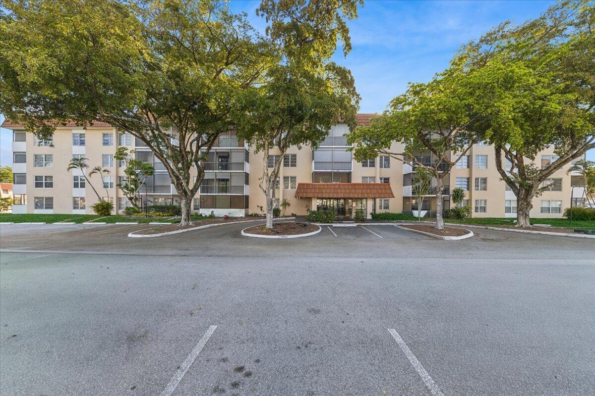A multi-story apartment building with a tan facade and a covered entrance sits behind parking — 4156 Inverrary Drive, Lauderhill FL 33319, LAUDERHILL, FL