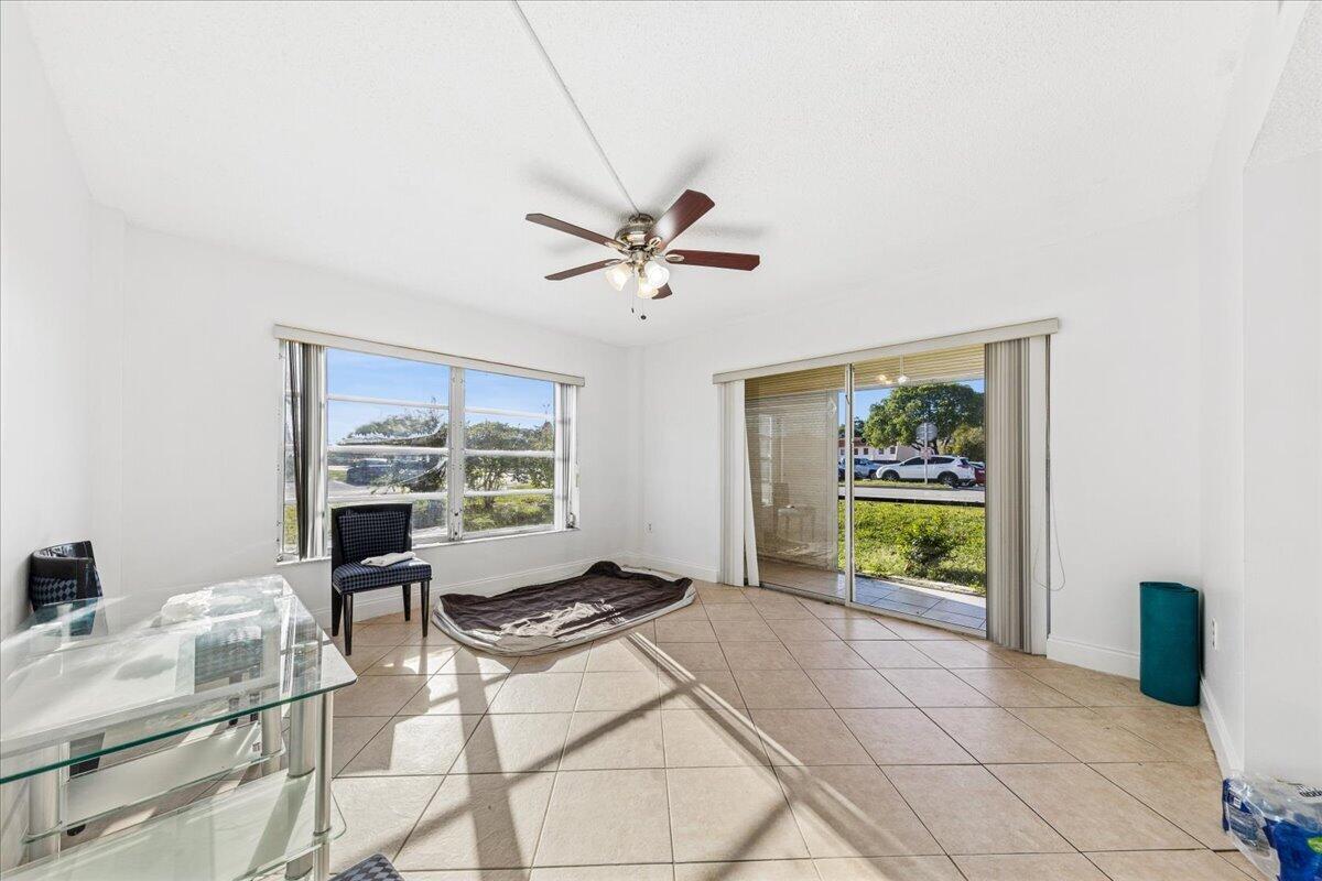 A bright room with tile floors, a ceiling fan, large windows, and a sliding glass door — 4156 Inverrary Drive, Lauderhill FL 33319, LAUDERHILL, FL