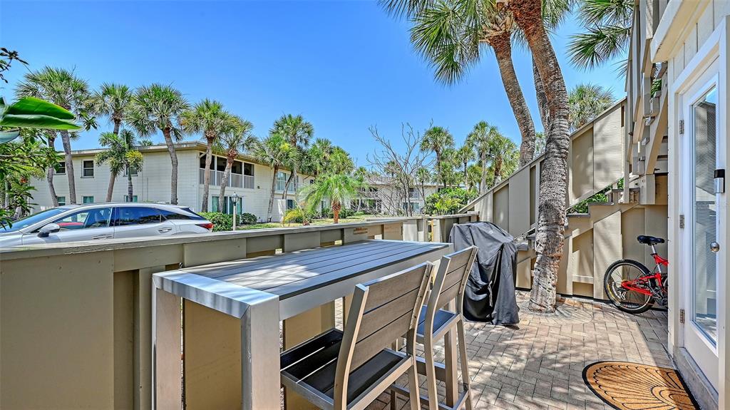 A patio features a high-top table with chairs, a covered grill, and a parked bicycle — 6750 GULF OF MEXICO DRIVE UNIT 171, LONGBOAT KEY, FL