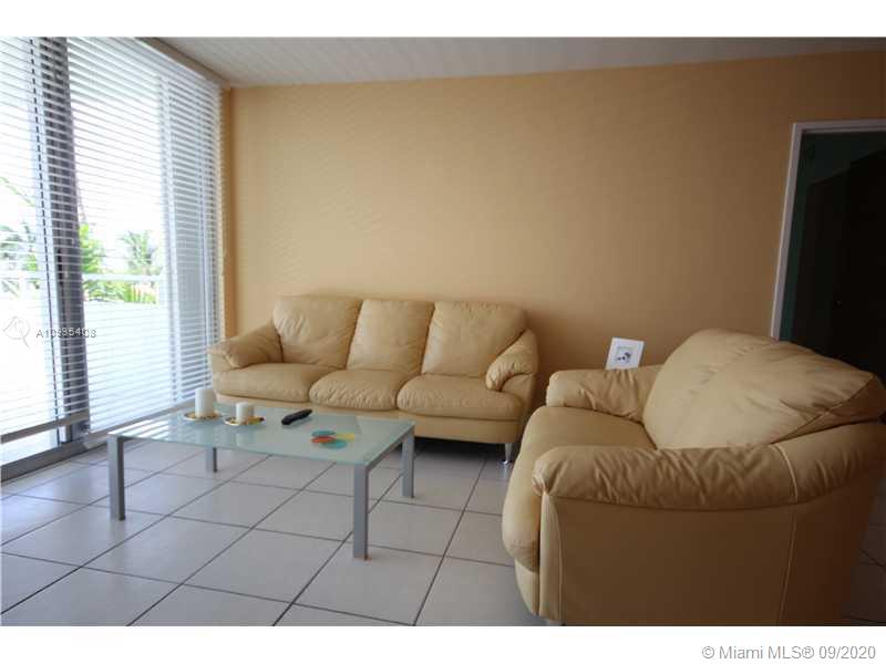 A living room features a beige leather sofa and loveseat on a tiled floor — 5161 COLLINS AV # 508, Miami Beach FL 33140, MIAMI BEACH, FL