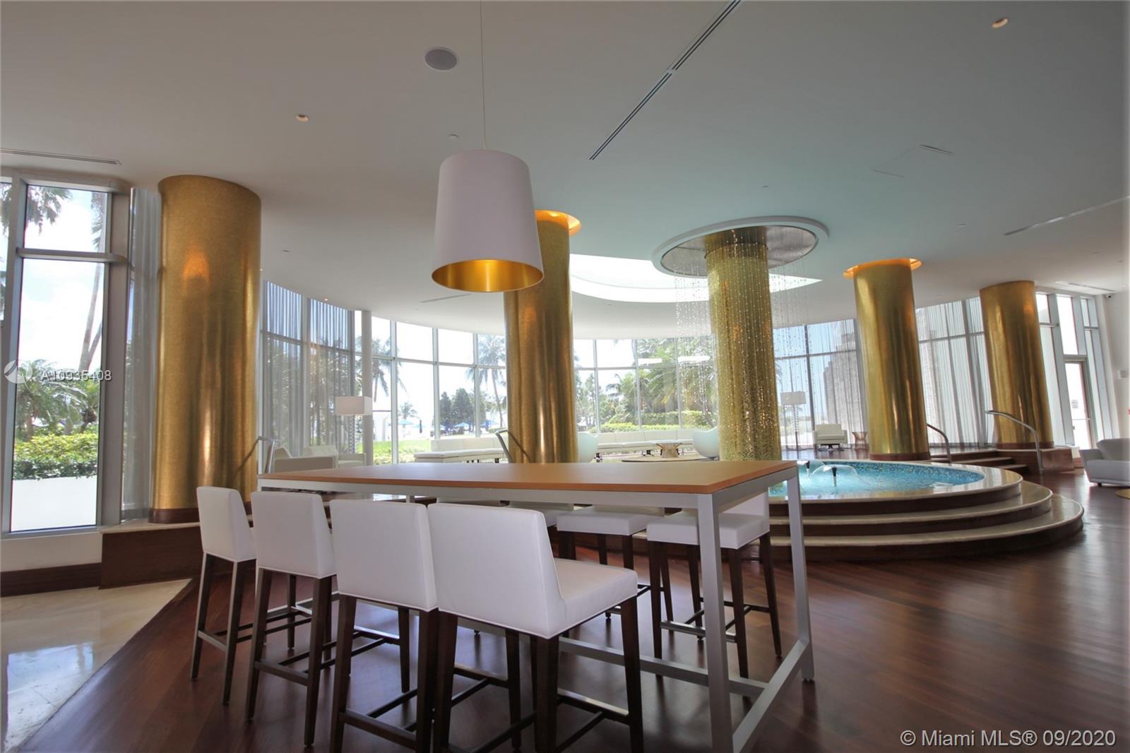A modern lounge features a high table with white stools, gold columns, and a circular fountain — 5161 COLLINS AV # 508, Miami Beach FL 33140, MIAMI BEACH, FL