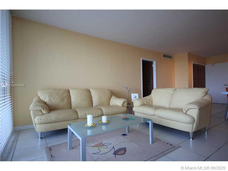 A living room features two cream-colored leather sofas, a glass coffee table, and tile flooring — 5161 COLLINS AV # 508, Miami Beach FL 33140, MIAMI BEACH, FL