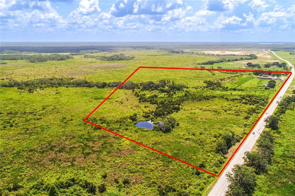 An aerial view shows a large, grassy plot of land outlined in red with a pond — 4706 COUNTY ROAD 557A, POLK CITY, FL