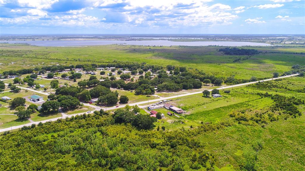 An aerial view shows a rural landscape with a road, scattered houses, and a lake — 4706 COUNTY ROAD 557A, POLK CITY, FL