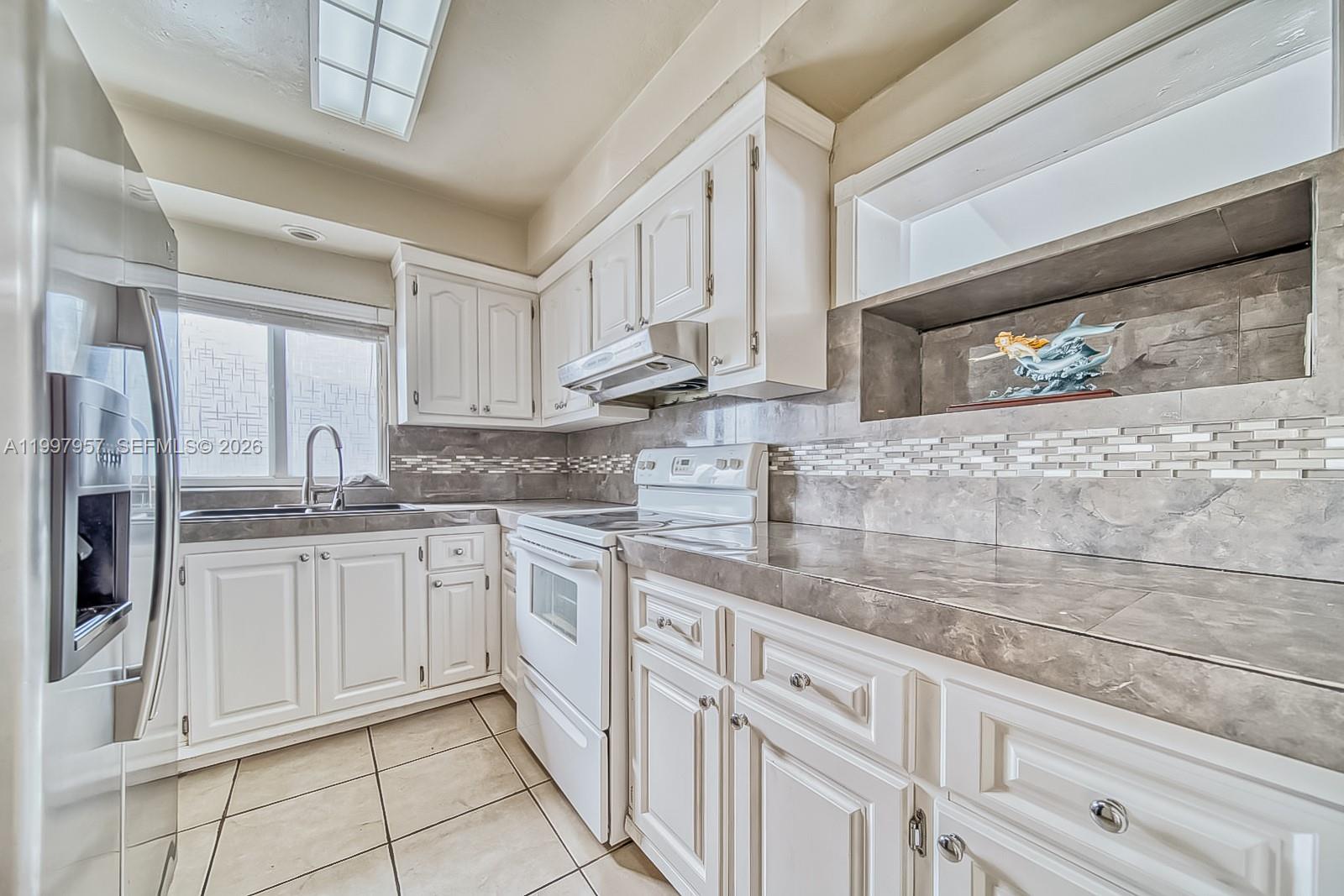 A kitchen features white cabinets, gray tile countertops, a tiled backsplash, and stainless steel appliances — 2171 SW 21st St, Miami FL 33145, MIAMI, FL