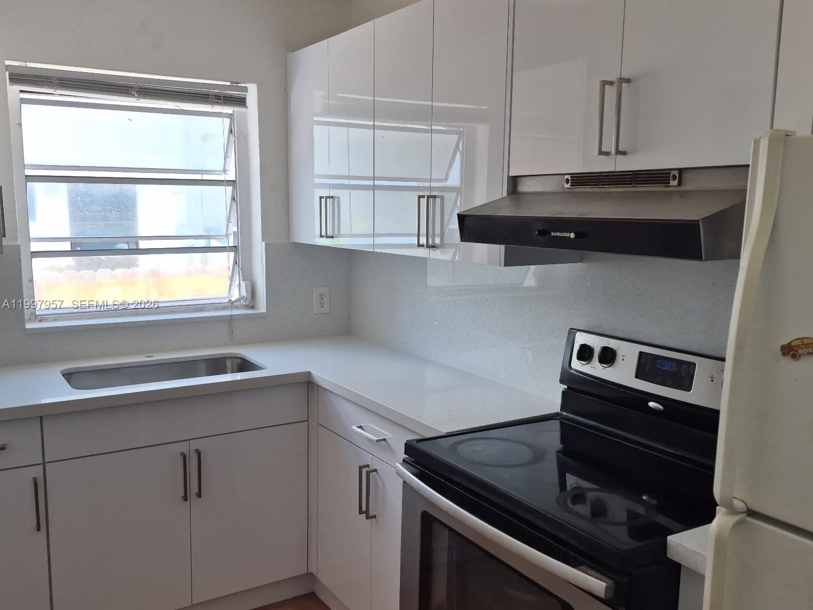 A kitchen features white cabinets, a quartz countertop, a stainless steel sink, and a stove — 2171 SW 21st St, Miami FL 33145, MIAMI, FL