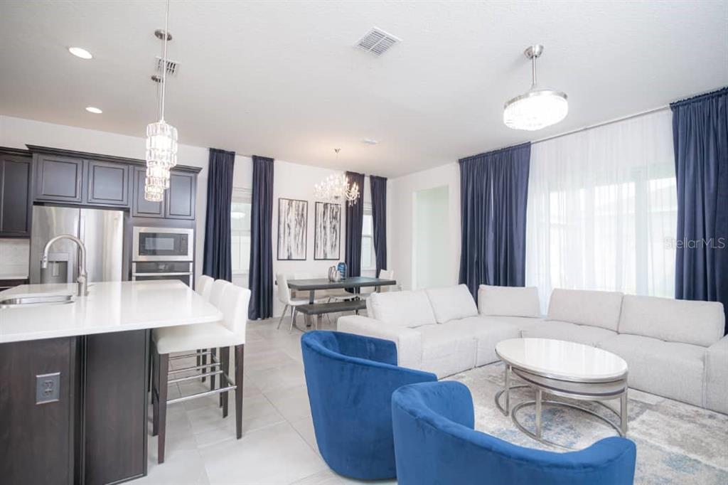 An open-concept kitchen, dining area, and living room feature dark cabinetry and blue accents — 15367 GILLIGAN COURT, WINTER GARDEN, FL