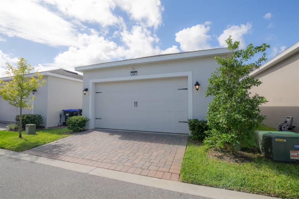 A single-story house exterior features a white garage door, a paved driveway, and landscaping — 15367 GILLIGAN COURT, WINTER GARDEN, FL