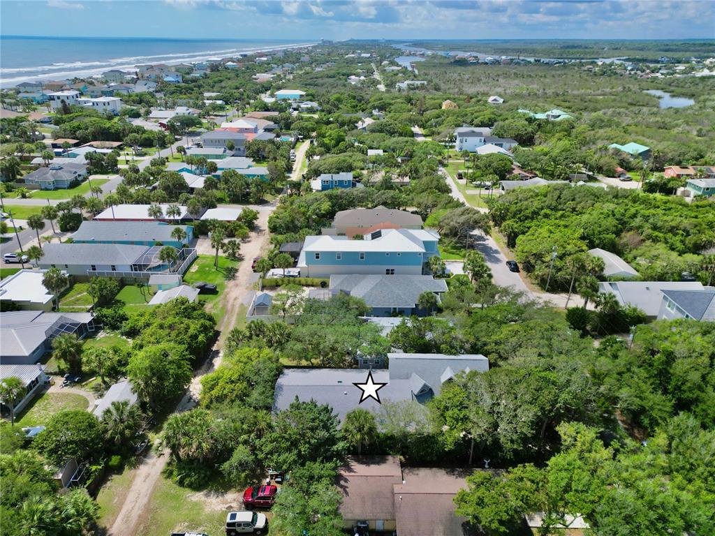An aerial view shows a coastal neighborhood with a star-marked house surrounded by lush trees — 2023 S FLAGLER AVENUE, FLAGLER BEACH, FL