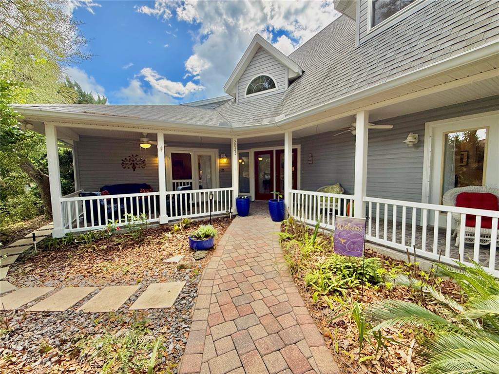 A gray house with a brick walkway leading to a covered porch and front entrance — 2023 S FLAGLER AVENUE, FLAGLER BEACH, FL