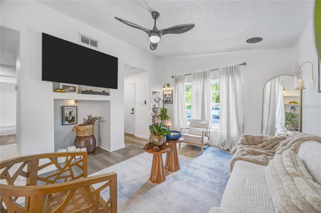 A living room features a wall-mounted television, a ceiling fan, and a light-colored area rug — 5811 MABEL STREET, TAMPA, FL