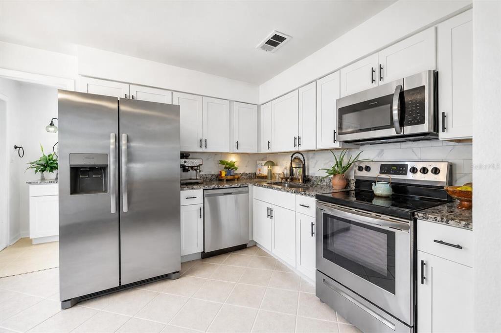 A living room with a ceiling fan, a wall-mounted television, and an open-concept dining area — 5811 MABEL STREET, TAMPA, FL