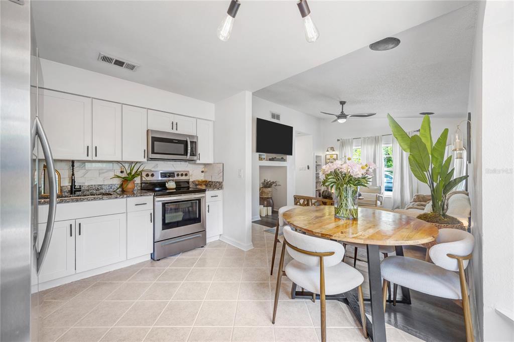 A white wall features a mounted television above a recessed niche with decor and lighting — 5811 MABEL STREET, TAMPA, FL