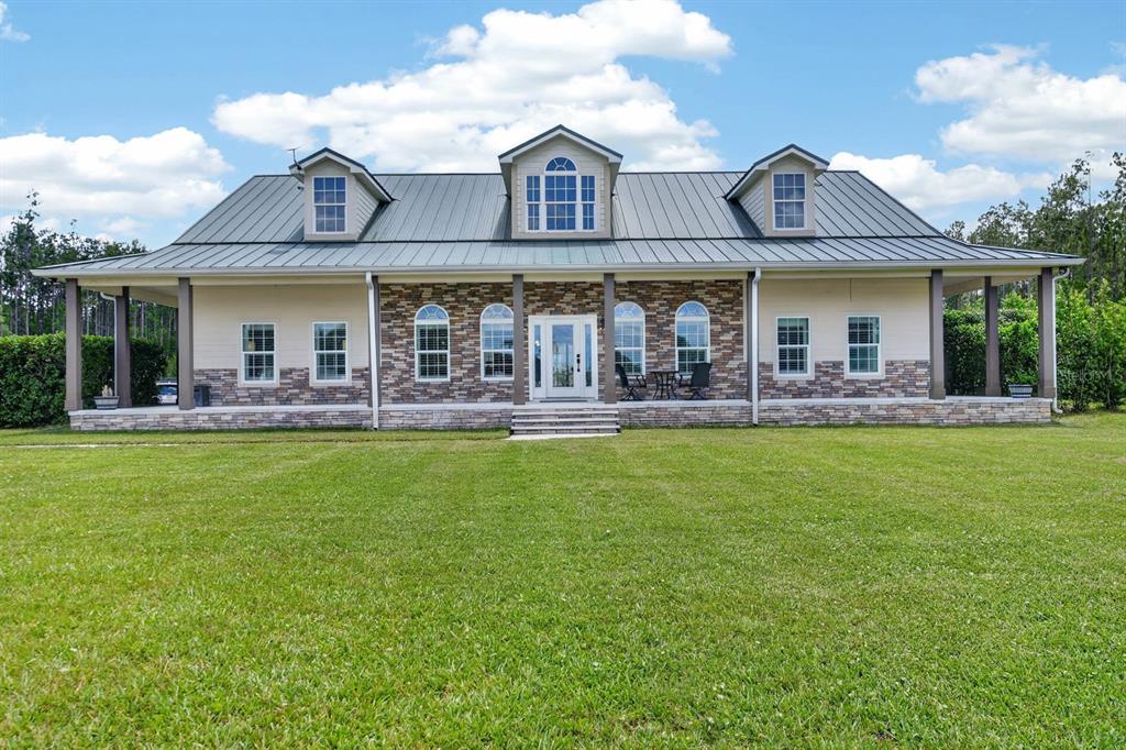 A single-story house with a metal roof, stone facade, and three dormer windows — 103 SWEETWATER TRAIL, BUNNELL, FL
