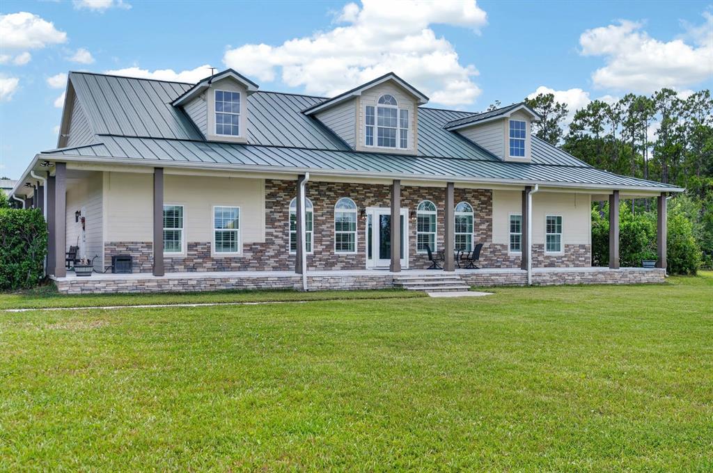 A two-story house with a metal roof, stone facade, and a wide front porch — 103 SWEETWATER TRAIL, BUNNELL, FL