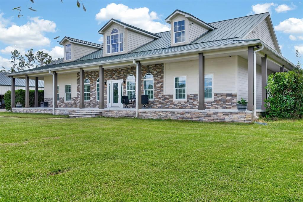 A single-story house with a metal roof, stone veneer siding, and a covered front porch — 103 SWEETWATER TRAIL, BUNNELL, FL