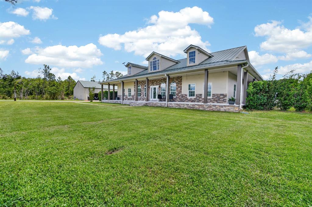 A single-story house with a metal roof, stone facade, and a large front porch — 103 SWEETWATER TRAIL, BUNNELL, FL