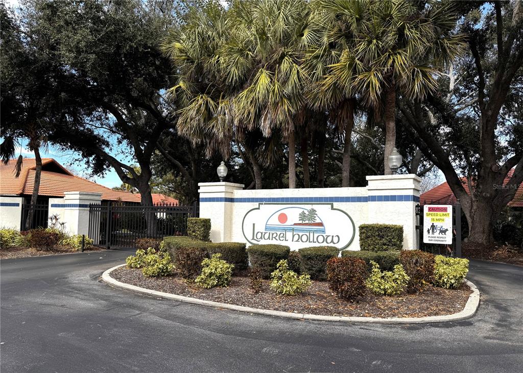 The entrance to the Laurel Hollow community features a stone sign, landscaping, and gated access — 229 LAUREL HOLLOW DRIVE UNIT 83, NOKOMIS, FL