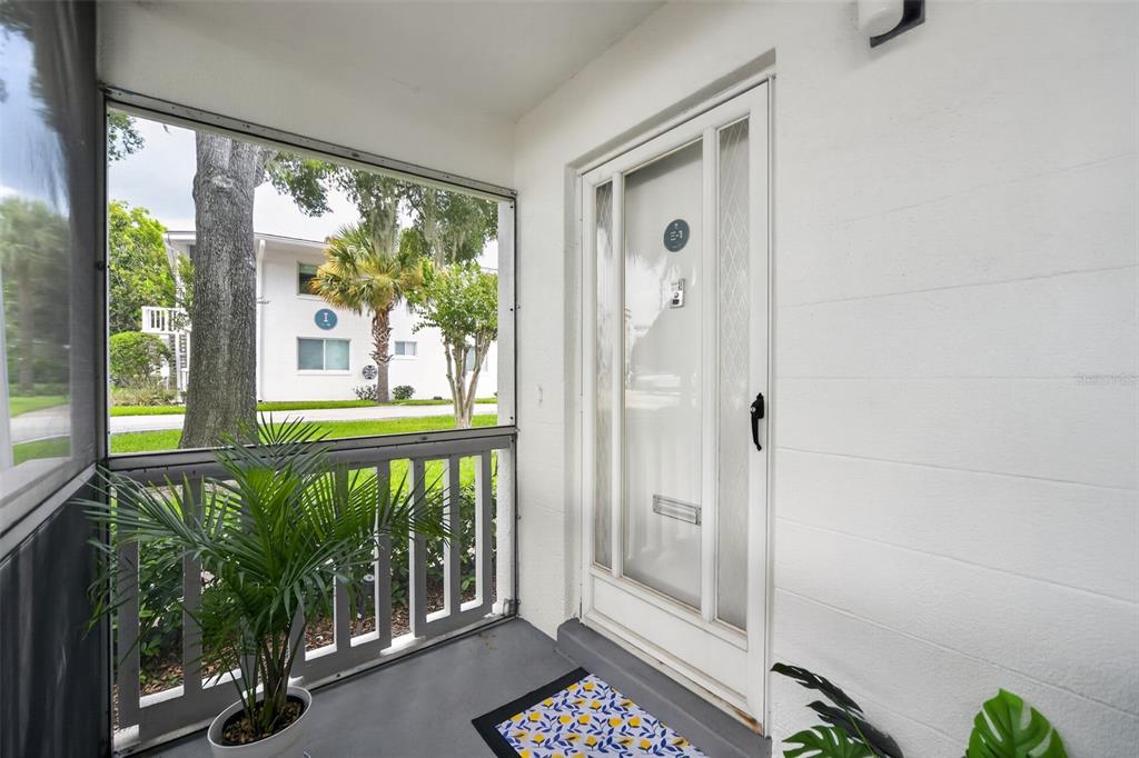 A screened-in porch features a white front door, a potted plant, and a patterned mat — 1140 S ORLANDO AVENUE UNIT E1, MAITLAND, FL