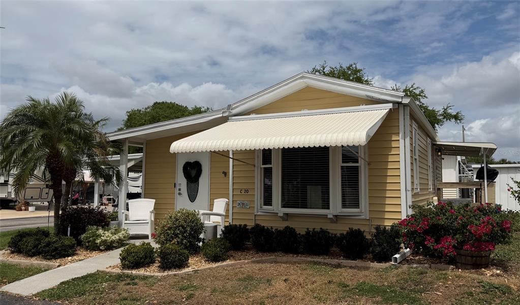 A yellow single-story home with a white awning, bay window, and front yard landscaping — 6633 53RD AVENUE E UNIT C-20, BRADENTON, FL
