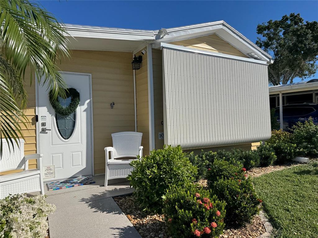 The exterior of a yellow house features a white front door and a large window shade — 6633 53RD AVENUE E UNIT C-20, BRADENTON, FL