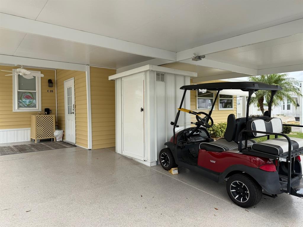 A yellow mobile home features a covered carport with a golf cart and storage shed — 6633 53RD AVENUE E UNIT C-20, BRADENTON, FL