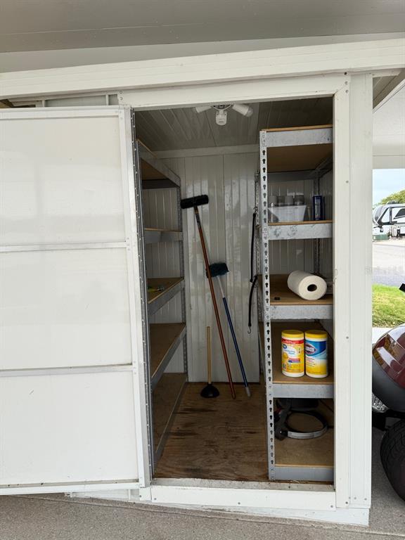 An outdoor storage shed features metal shelving units and a wooden floor — 6633 53RD AVENUE E UNIT C-20, BRADENTON, FL