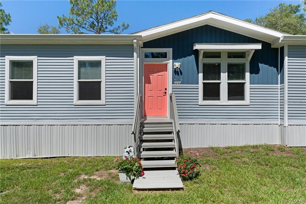 A single-story house with light blue siding, a dark blue gable, and a coral front door — 2220 N DONOVAN AVENUE, CRYSTAL RIVER, FL