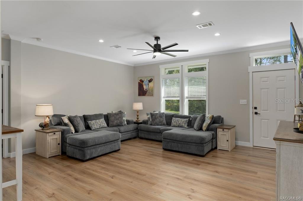 A living room features gray sectional sofas, light wood flooring, and a ceiling fan — 2220 N DONOVAN AVENUE, CRYSTAL RIVER, FL