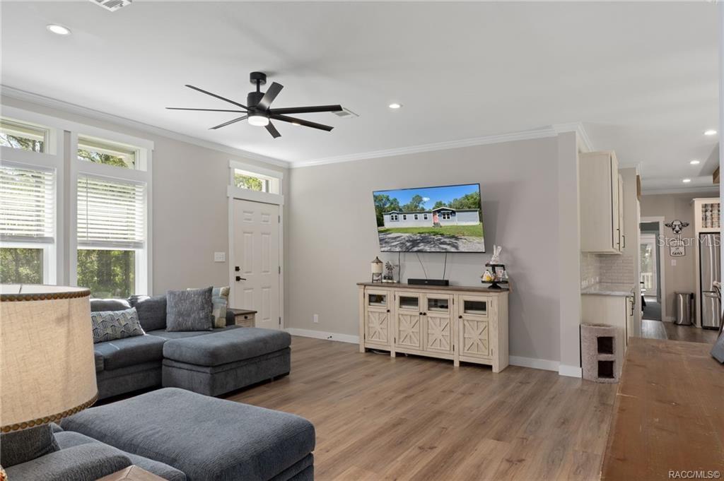 A living room features gray walls, wood-look flooring, a sectional sofa, and a wall-mounted television — 2220 N DONOVAN AVENUE, CRYSTAL RIVER, FL