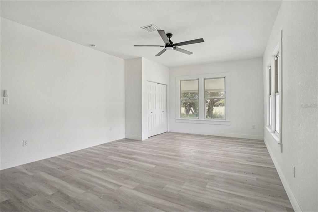 An empty bedroom features white walls, light wood-look flooring, a ceiling fan, and a closet — 41333 STATE ROAD 19, UMATILLA, FL
