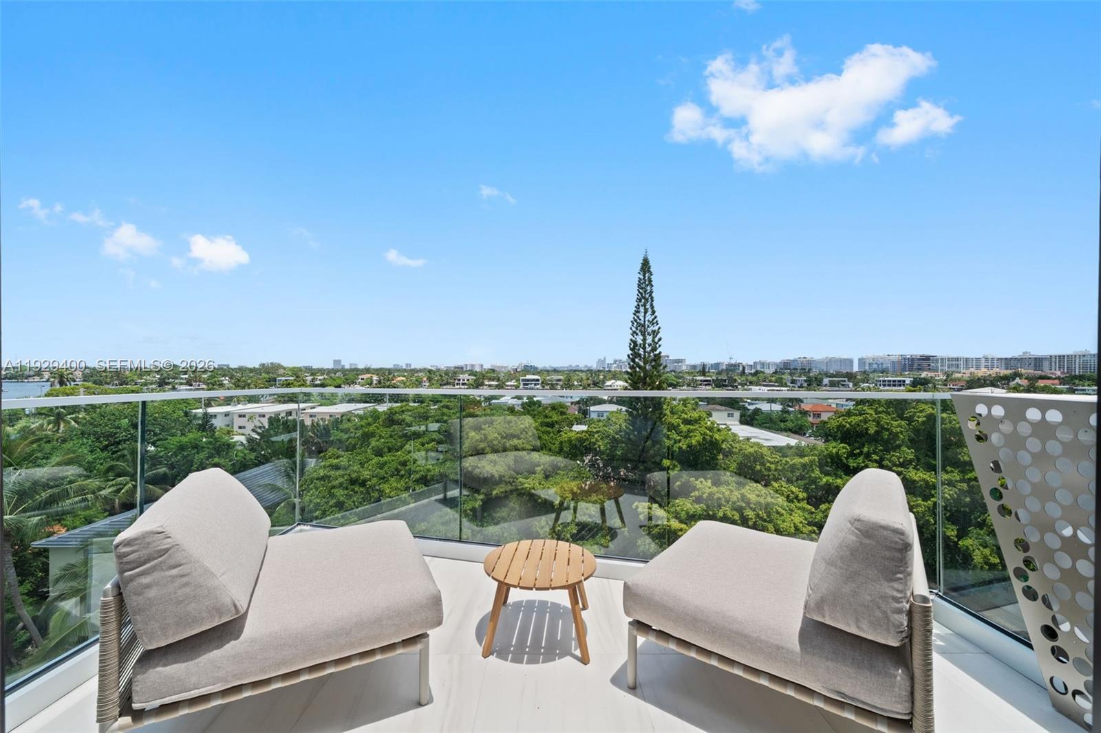 A balcony features two beige armchairs, a small wooden table, and a glass railing — 756 84th St, Miami Beach FL 33141, MIAMI BEACH, FL