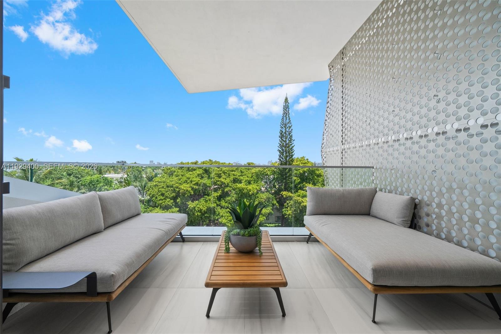 A balcony features two gray sofas, a wooden coffee table, and a perforated metal screen — 756 84th St, Miami Beach FL 33141, MIAMI BEACH, FL