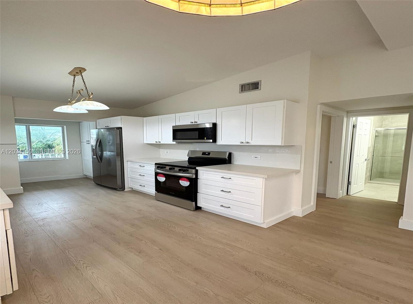 A modern kitchen features white cabinets, stainless steel appliances, and light wood-look flooring — 136 Marina Ave, Key Largo FL 33037, KEY LARGO, FL