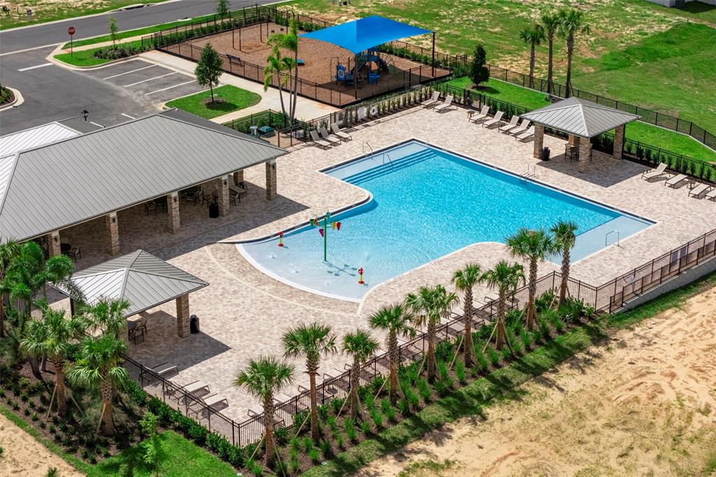 An aerial view of a community swimming pool, splash pad, playground, and covered patio areas — 27313 AFRICAN FISH COURT, HOWEY IN THE HILLS, FL